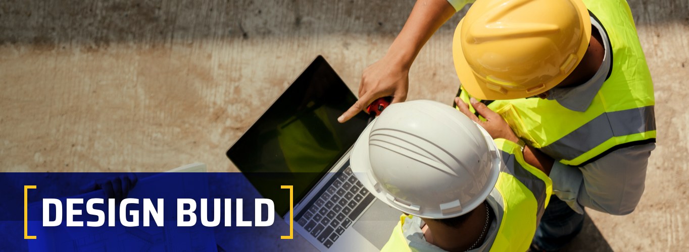 Design Build at Witwer Construction. Construction workers looking at laptop on project build site.