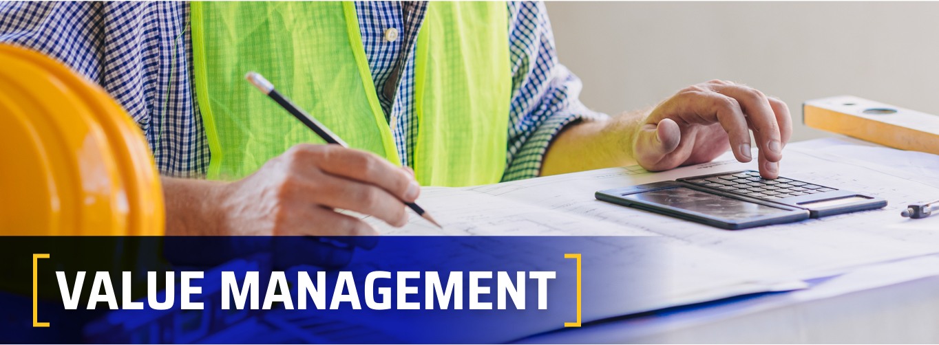 Value Management at Witwer Construction. Employee sitting at desk using calculator.